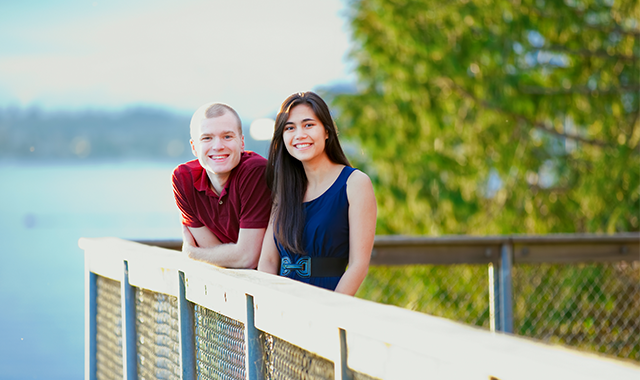 Young interracial couple standing together on wooden pier overlo